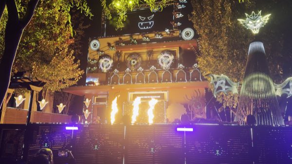 The house lit in gold with three flame bursts in front, bats across the roof, and a glowing dragon atop the mega tree